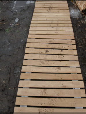 Economy version of the garden path: wooden walkway of pallets with their hands