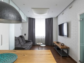 Белая гостиная с деревянным столом и серым диваном