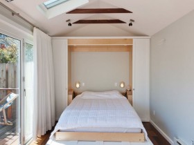 Маленька біла спальня з великими вікнами