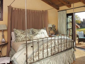 Кровать под балдахином в спальне с деревянным скошенным потолком