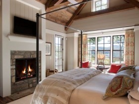 Спальня с камином и деревянным скошенным потолком