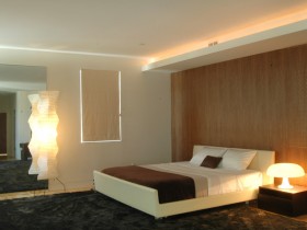 Современный интерьер спальни с черным ковром и деревянной стенкой