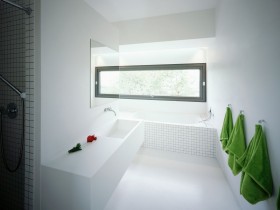 Белая ванная комната, которую украшают зеленые полотенца