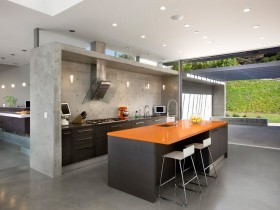 Черный кухонный островок с оранжевой столешницей в коттедже стиля конструктивизм