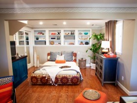 Маленькая спальня с деревянным полом и черным комодом