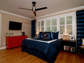 Светлая спальня с темно-синей кроватью и красным комодом