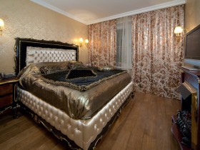 Спальня с большой деревянной кроватью, отделанной позолотой
